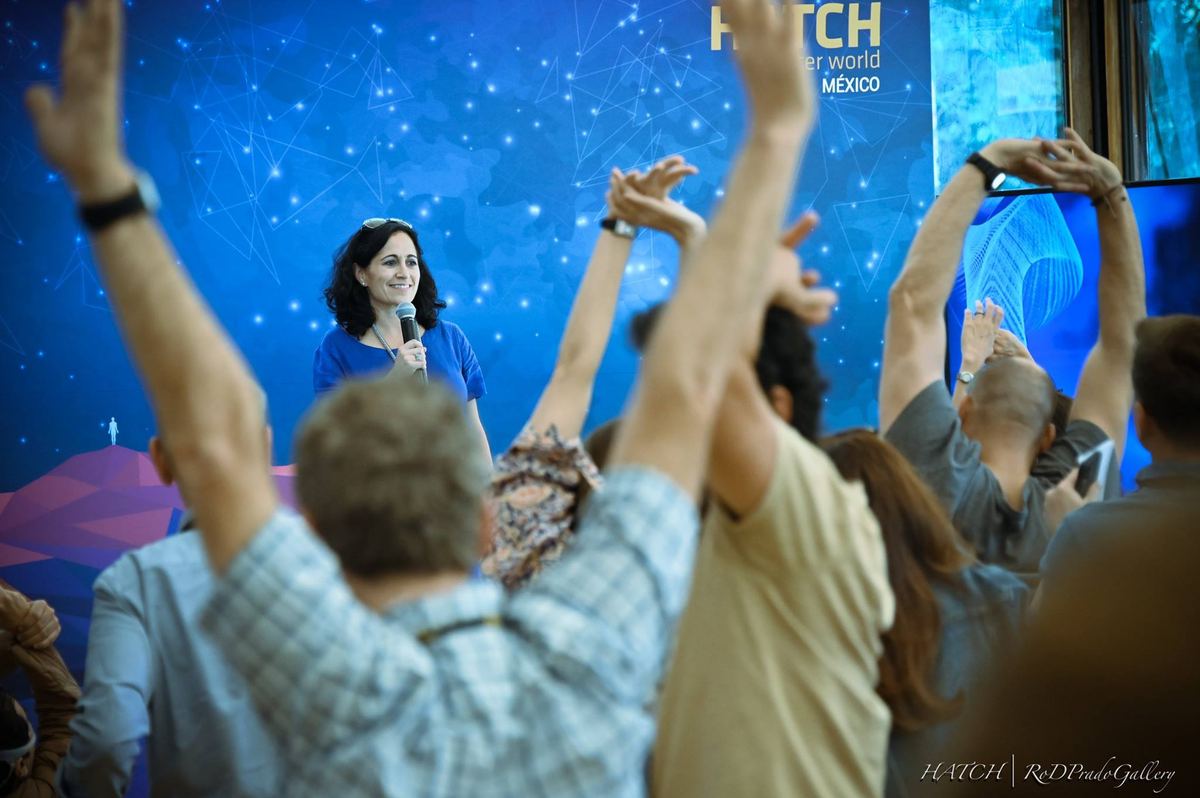 A speaker on the HATCH stage smiles as most of the audience raises their hands in response.